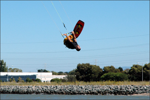 A kitesurfer, flipping across the bay.